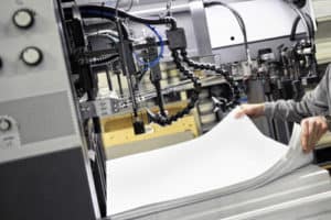 Worker Preparing Large White Papers for Print at the Printing Machine